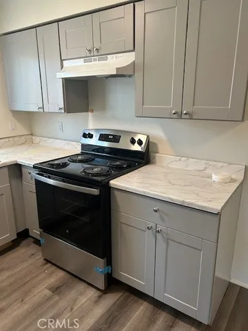 a kitchen with granite countertop white cabinets and a stove with wooden floor