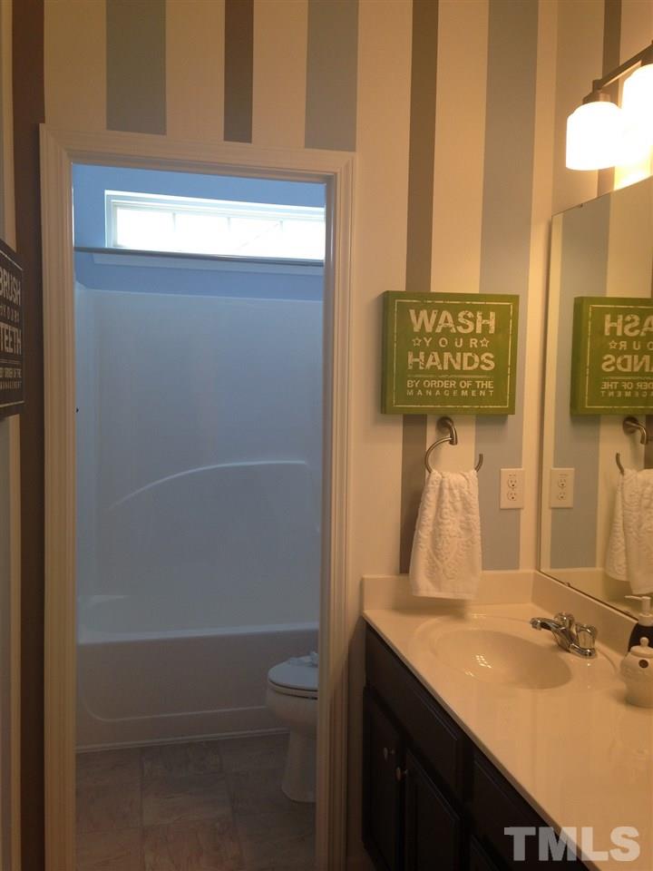 826 Wickham Ridge Road, Unit 6 Apex, NC 27539 - Photo 21 of 25 a bathroom with a sink a toilet and mirror