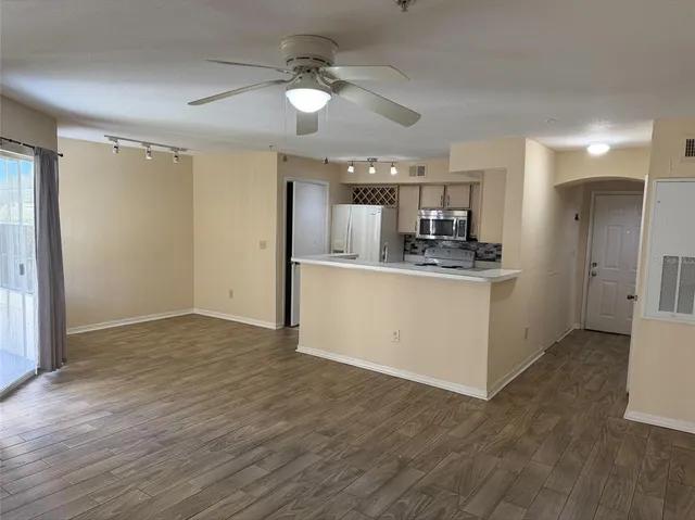 a view of an empty room with window and wooden floor