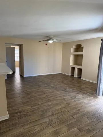 a view of an empty room with window and wooden floor