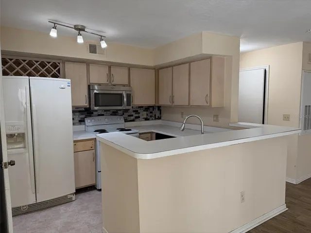 a view of a kitchen with a sink a refrigerator a ceiling fan and wooden floor