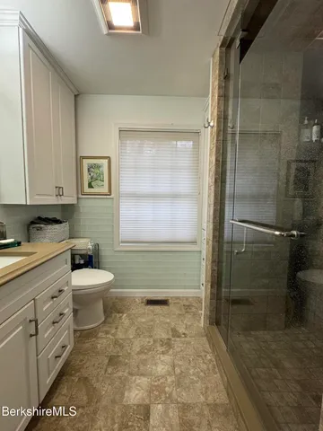 a bathroom with a granite countertop toilet a sink a shower and a mirror