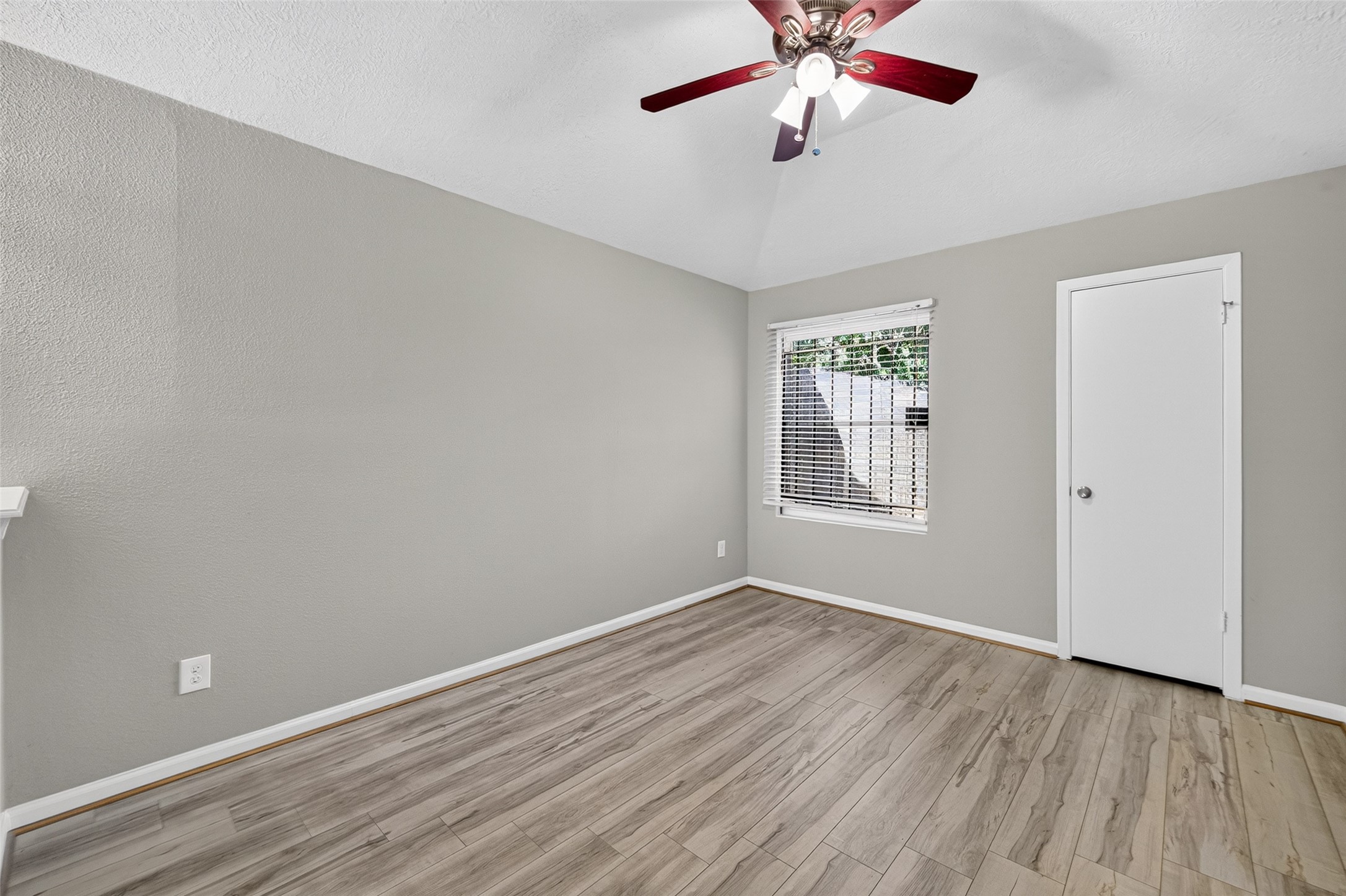 16203 Beck Ridge Drive Houston, TX 77053 - Photo 24 of 29 Spacious room with sleek wood flooring, a modern ceiling fan, and abundant natural light from a large window.