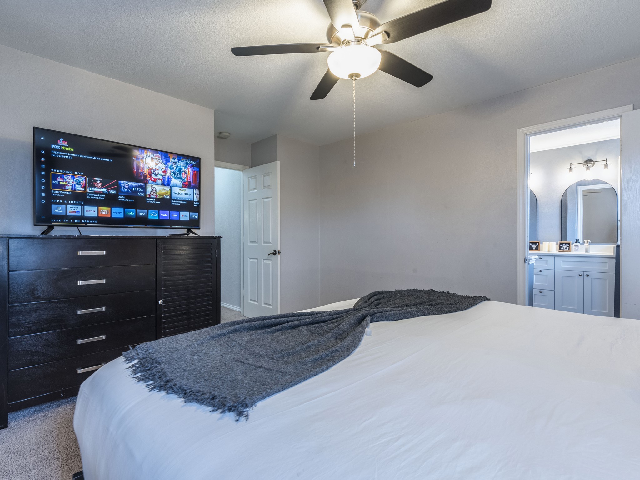 1415 Roxanne's Run Pflugerville, TX 78660 - Photo 18 of 30 A well-lit bedroom features a ceiling fan, plush carpeting, and direct access to a private bathroom.