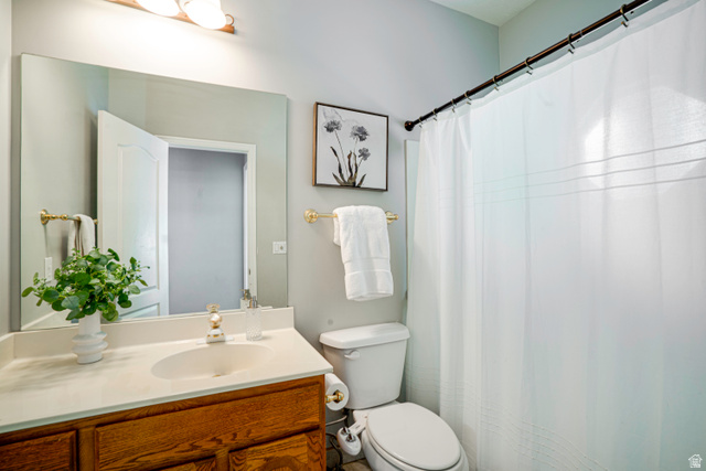 1433 Forge Way Draper, UT 84020 - Photo 26 of 29 Bathroom featuring a wood-finish vanity with a light-colored countertop, an undermount sink, and a large wall-mounted mirror