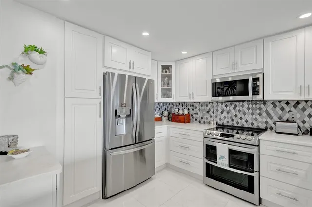 a kitchen with stainless steel appliances a refrigerator sink and white cabinets