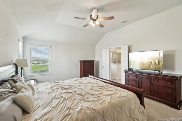 a bedroom with a large bed and a flat tv screen on dresser