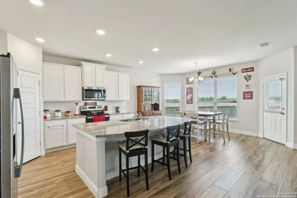 a kitchen with stainless steel appliances a dining table chairs microwave and cabinets