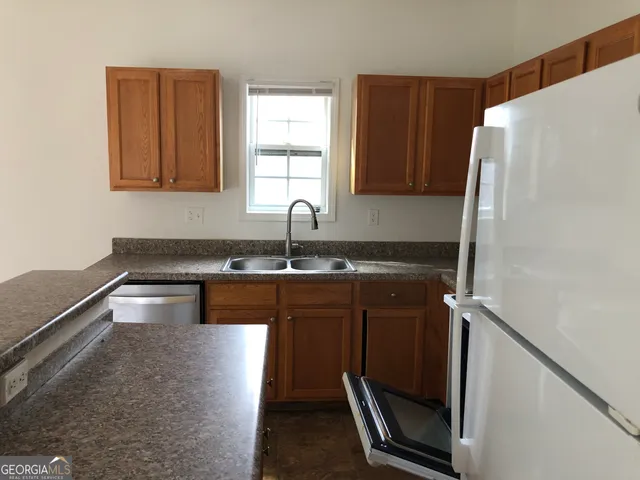 a kitchen with granite countertop a refrigerator and a sink