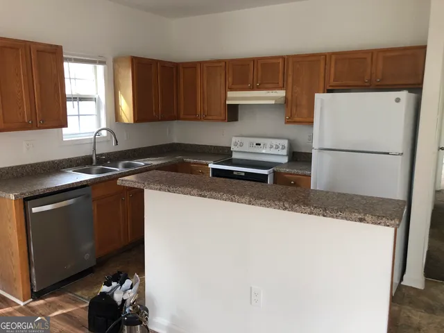 a kitchen with granite countertop a sink a stove and a refrigerator