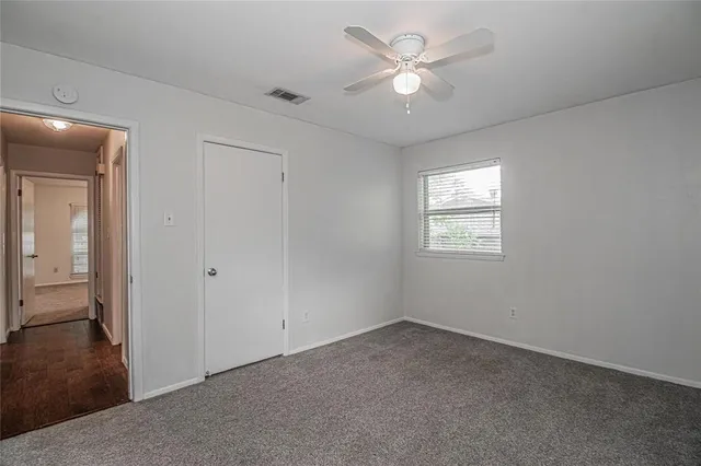 an empty room with a window and a ceiling fan
