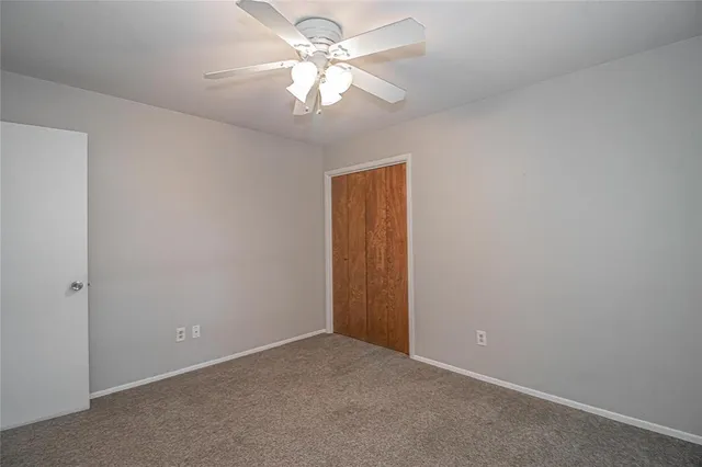 an empty room with a chandelier fan and closet