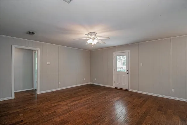 a view of a room with wooden floor and a ceiling fan