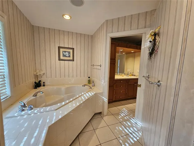 a bathroom with a granite countertop tub sink and mirror