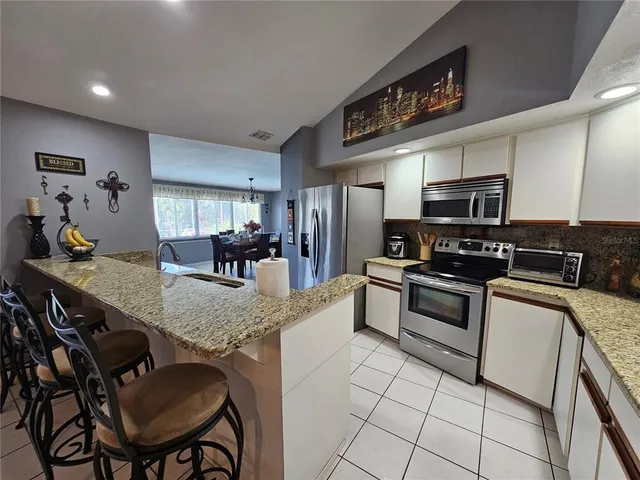 a kitchen with stainless steel appliances granite countertop a stove top oven a sink a dining table and chairs