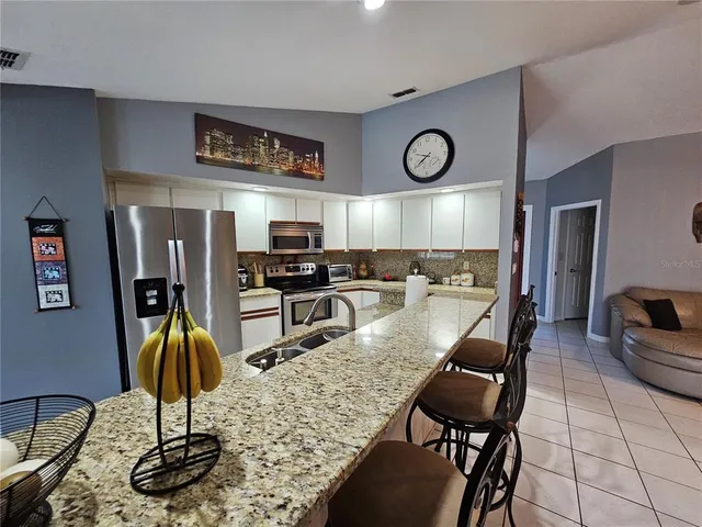 a kitchen with stainless steel appliances granite countertop a sink refrigerator stove and chairs