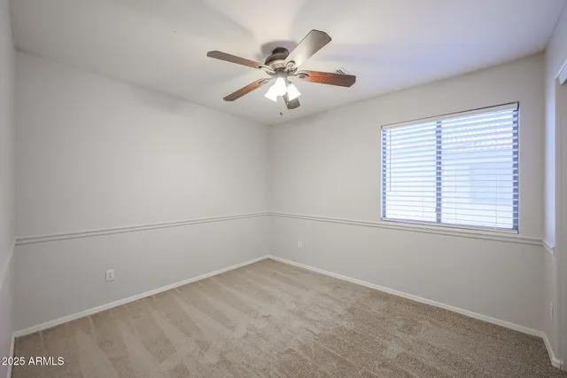 an empty room with a window and a fan