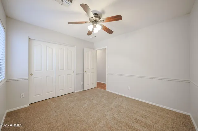 an empty room with closet and ceiling fan