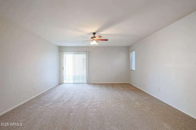 an empty room with a window and a ceiling fan