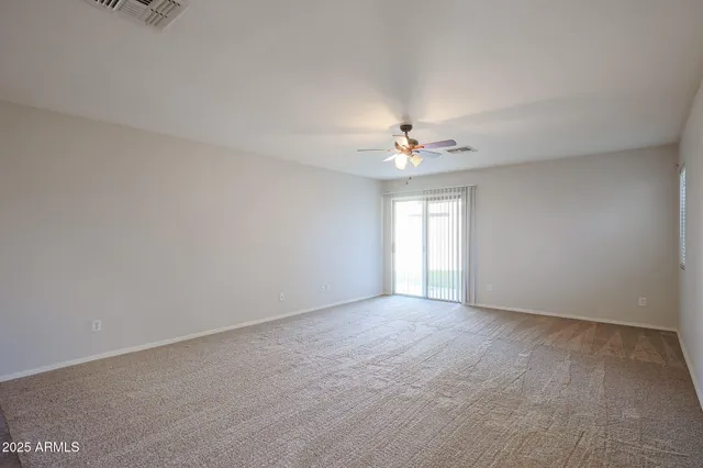 a view of an empty room with chandelier fan