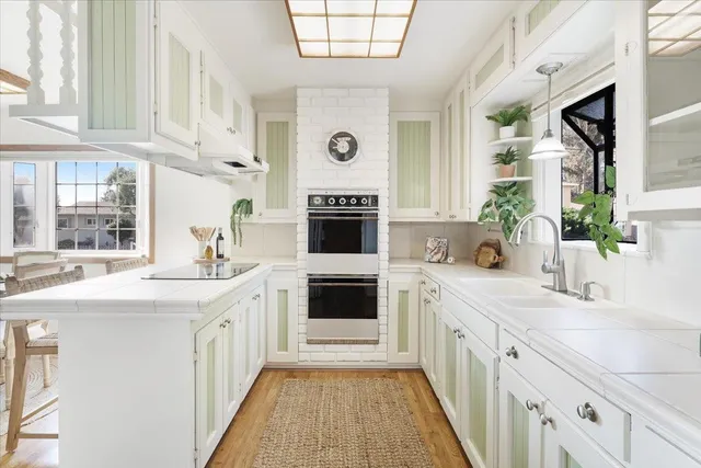 a large white kitchen with a sink and a stove top oven