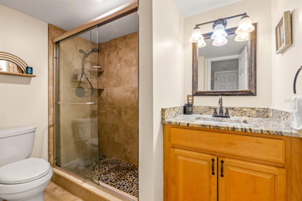 8911 Blind Pass Road, Unit 223 St. Pete Beach, FL 33706 - Photo 11 of 27 a bathroom with a granite countertop sink toilet and shower