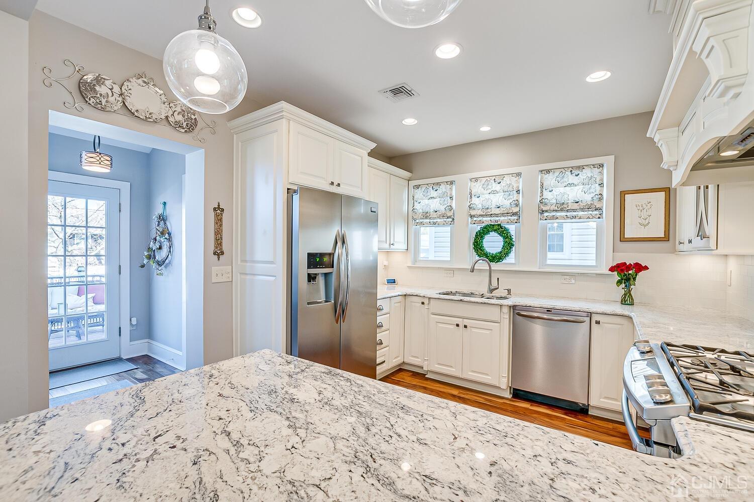 29 Jefferson Avenue Edison, NJ 08837 - Photo 15 of 36 a kitchen with stainless steel appliances granite countertop a refrigerator a stove a sink dishwasher a dining table and chairs with wooden floor