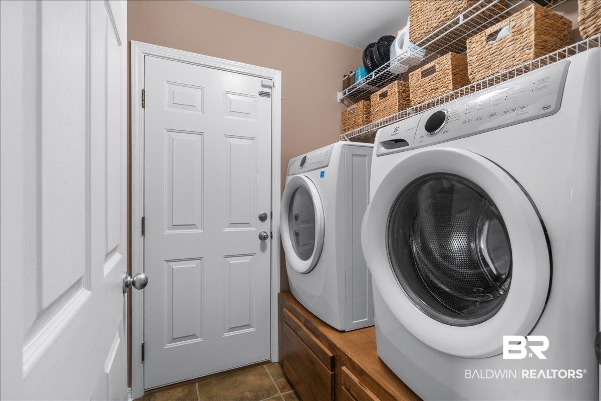 8952 Sherman Road Foley, AL 36535 - Photo 41 of 41 Dedicated laundry area featuring a front-load washer and dryer, elevated on wood-finish pedestals, and complemented by wire shelving for organized storage