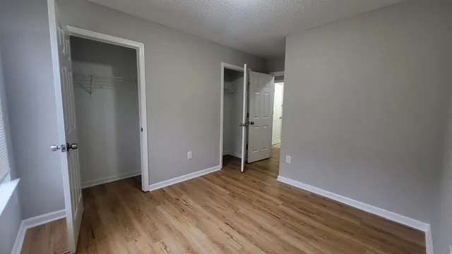 a view of an empty room with wooden floor and closet
