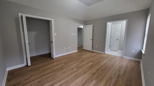 a view of an empty room with wooden floor and closet