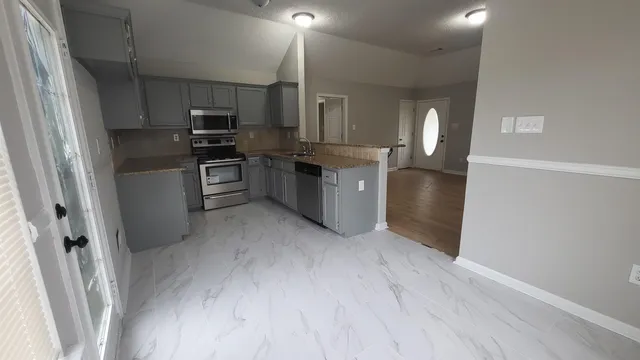 a kitchen with cabinets wooden floor and stainless steel appliances