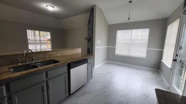 a kitchen with granite countertop a sink stove and cabinets