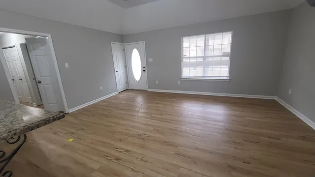 an empty room with wooden floor and windows