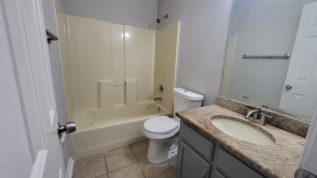 a bathroom with a granite countertop sink a toilet a mirror and shower