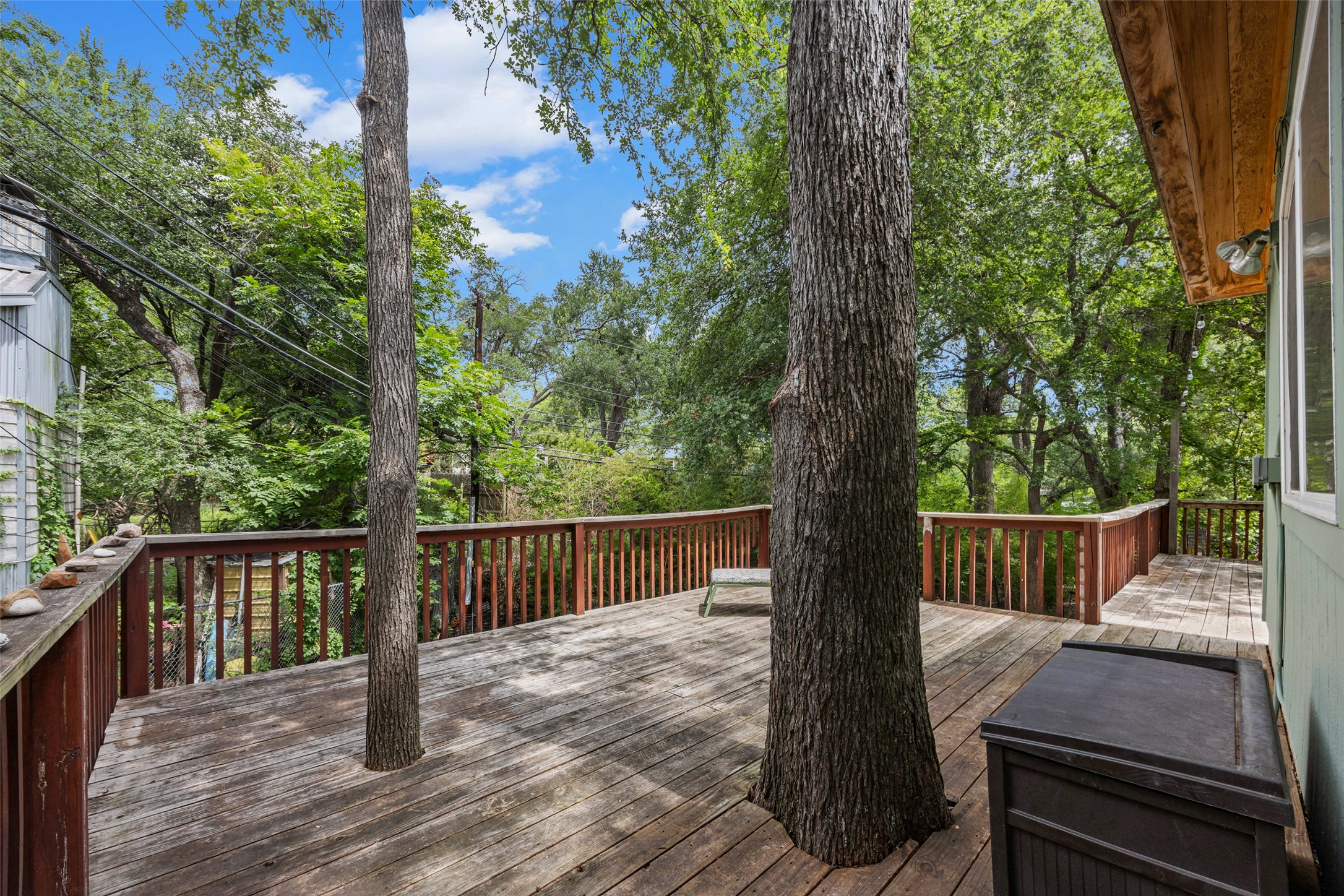 3302 Cherrywood Road Austin, TX 78722 - Photo 19 of 26 A spacious wooden deck with natural tree integrations offers a seamless outdoor living experience amidst lush greenery.