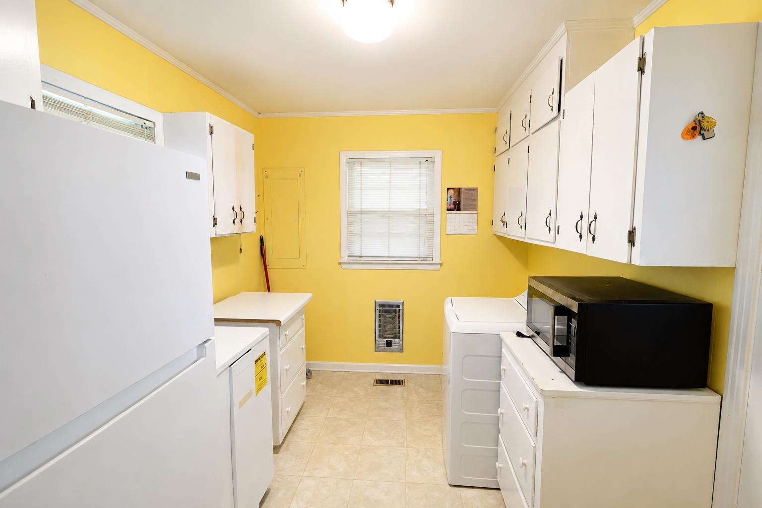 2000 Culbreath Road Covington, TN 38019 - Photo 14 of 16 Galley-style utility room featuring ample white cabinetry, a single window with blinds, and light-toned tile flooring
