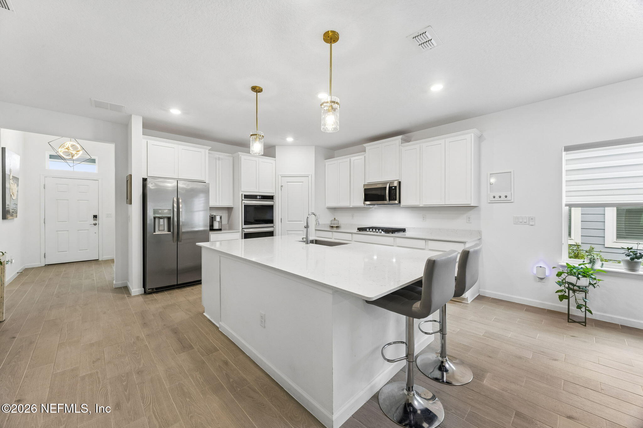 75626 Pondside Lane Yulee, FL 32097 - Photo 3 of 95 a kitchen with stainless steel appliances kitchen island granite countertop a refrigerator oven a sink dishwasher and white cabinets with wooden floor