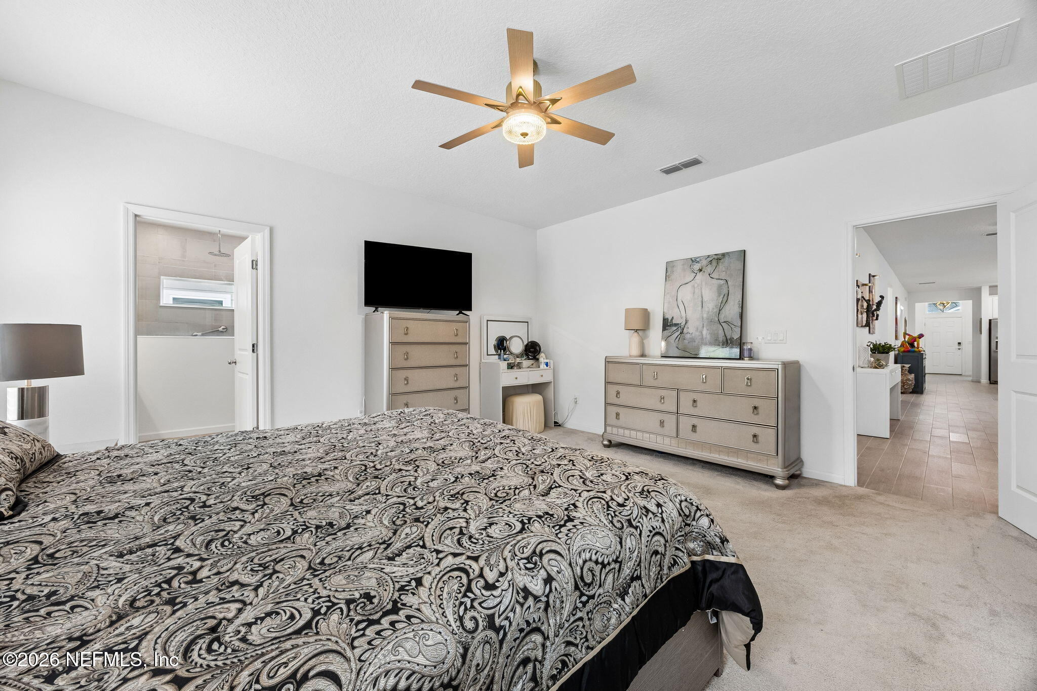75626 Pondside Lane Yulee, FL 32097 - Photo 31 of 95 a bedroom with a large bed and a flat tv screen on dresser