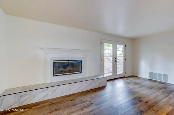 an empty room with wooden floor fireplace and windows