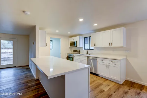 a large kitchen with wooden floor and white cabinets