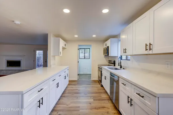 a large kitchen with stainless steel appliances granite countertop a lot of counter space and wooden floors