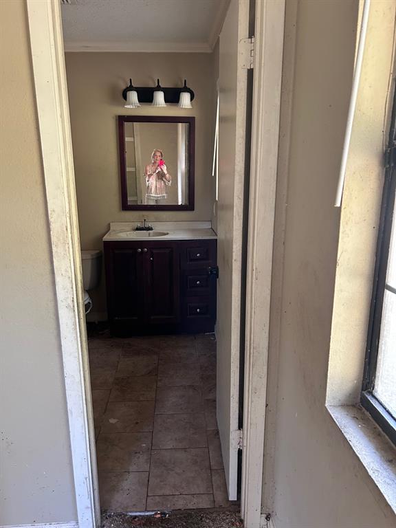 13550 Johns Gin Road Keithville, LA 71047 - Photo 3 of 11 Half bath with crown molding, vanity, and tile patterned flooring