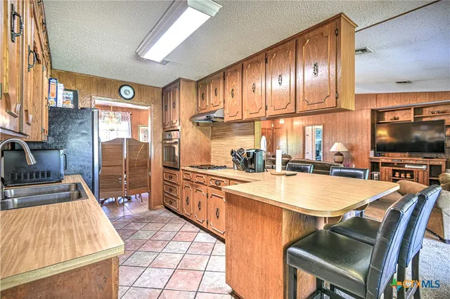 a kitchen with stainless steel appliances granite countertop a stove a sink and a refrigerator with wooden floor