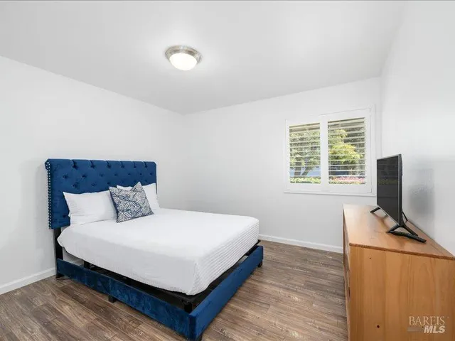 a bedroom with a bed table and a flat screen tv