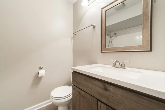 a bathroom with a granite countertop sink vanity mirror and toilet