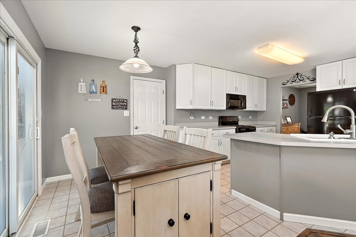 898 Meadowbrook Road Elwood, IL 60421 - Photo 7 of 30 a kitchen with stainless steel appliances a stove a sink dishwasher a refrigerator with white cabinets and wooden floor