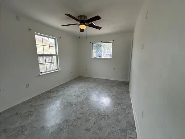 an empty room with windows and fan