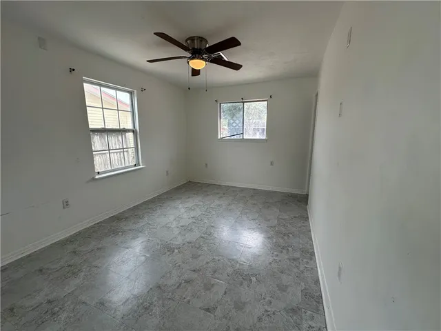 an empty room with windows and fan