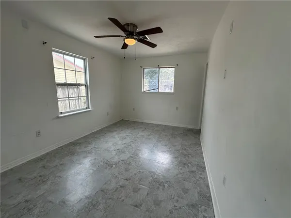 an empty room with windows and ceiling fan view