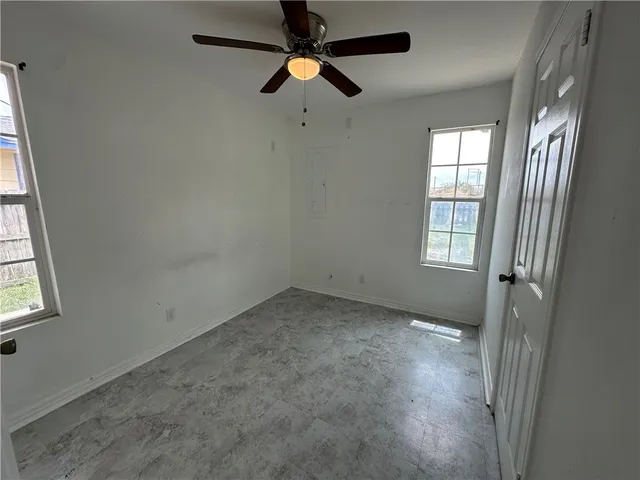 an empty room with windows and fan